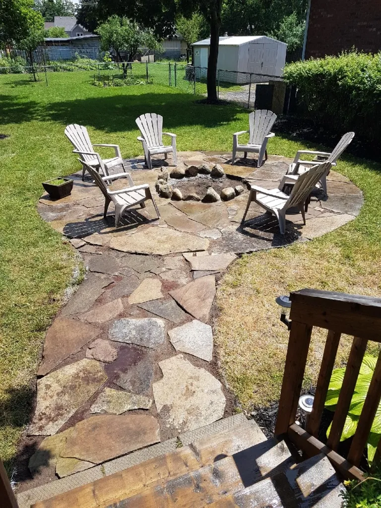 Finished fire pit with natural stone pathway and Muskoka chairs by Martin Services