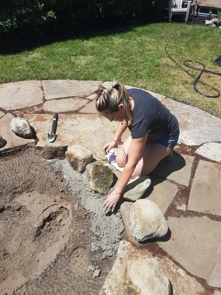 Setting natural stones into mortar for a custom fire pit built by Martin Services