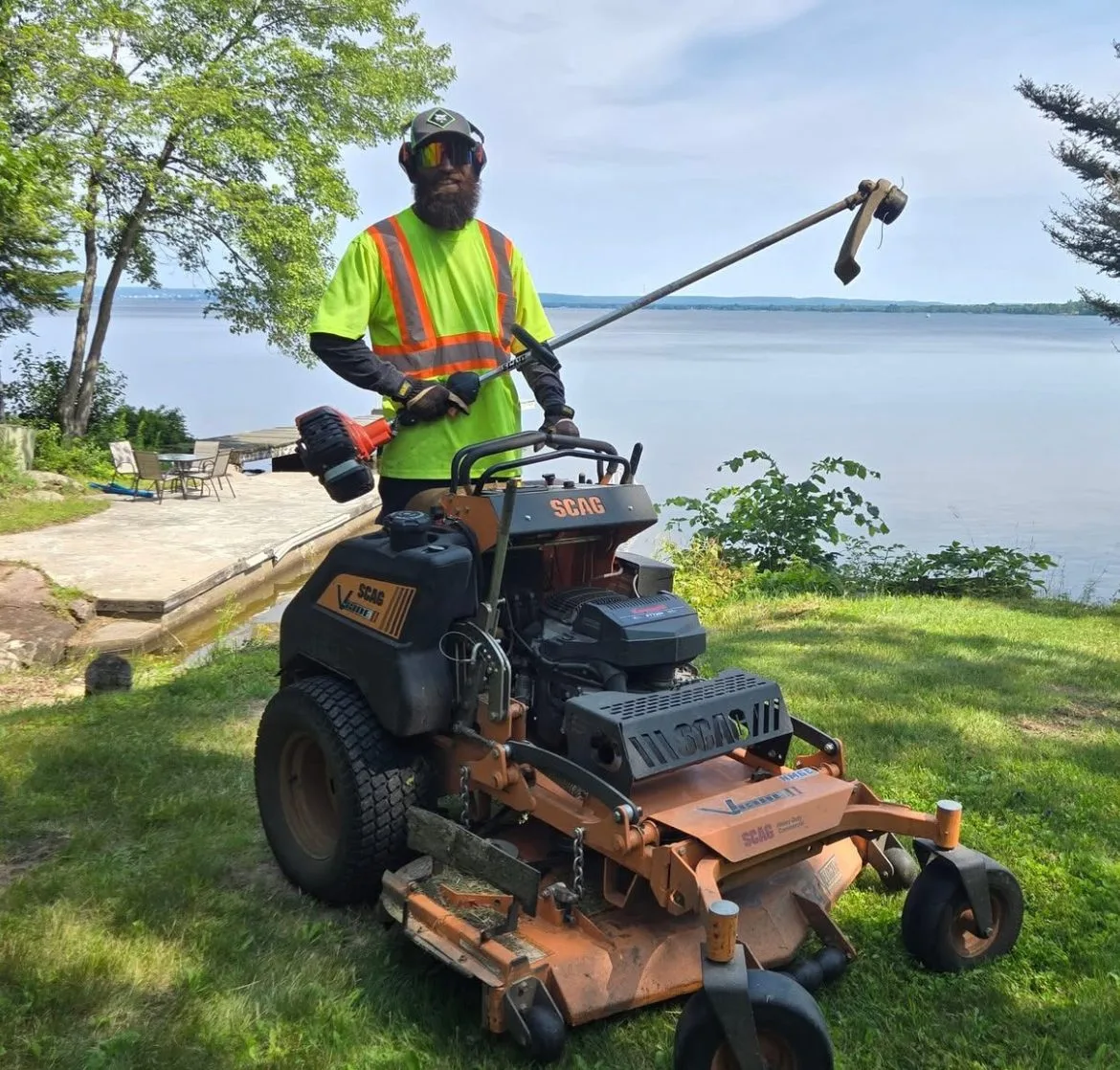 Martin Services crew member operating a Scag stand-on mower on a lakefront property in Northern Ontario