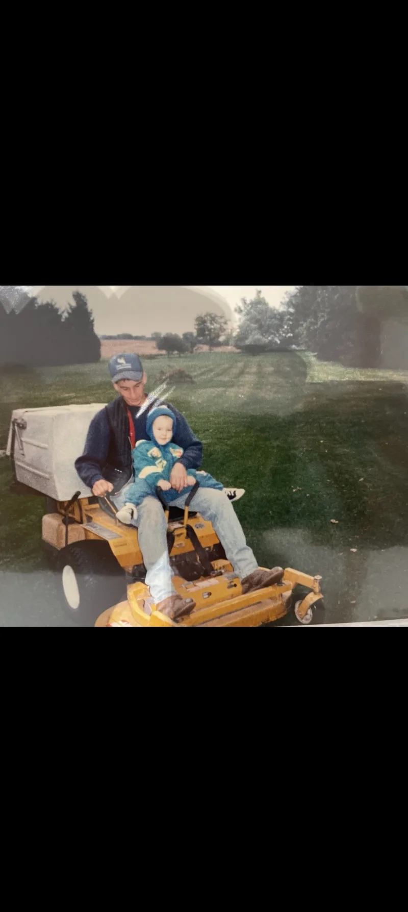 Keith Martin with young Brody on a mower — the beginning of a family legacy in lawn care