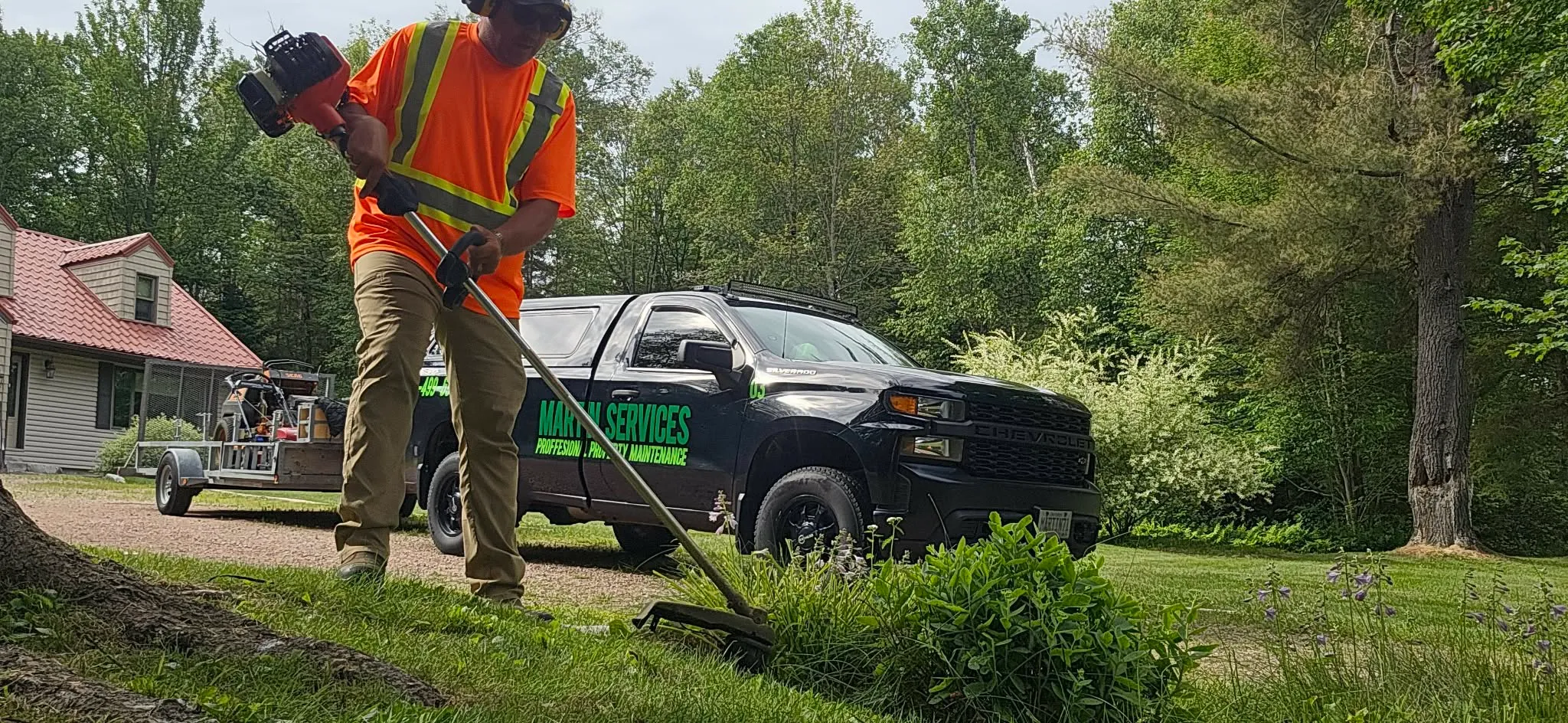 Martin Services crew member trimming with commercial string trimmer on a residential property