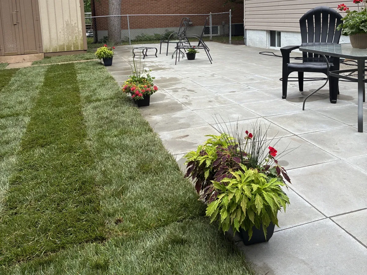 Large stone slab patio with fresh sod and planters in a residential backyard, built by Martin Services